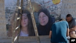 Palestinians hang a poster showing Nariman Tamimi, right, and her daughter, Ahed, during preparations for their upcoming release from an Israeli prison after serving an eight-month sentence, at the family house in the West Bank village of Nabi Saleh, west of Ramallah, July 28, 2018.
