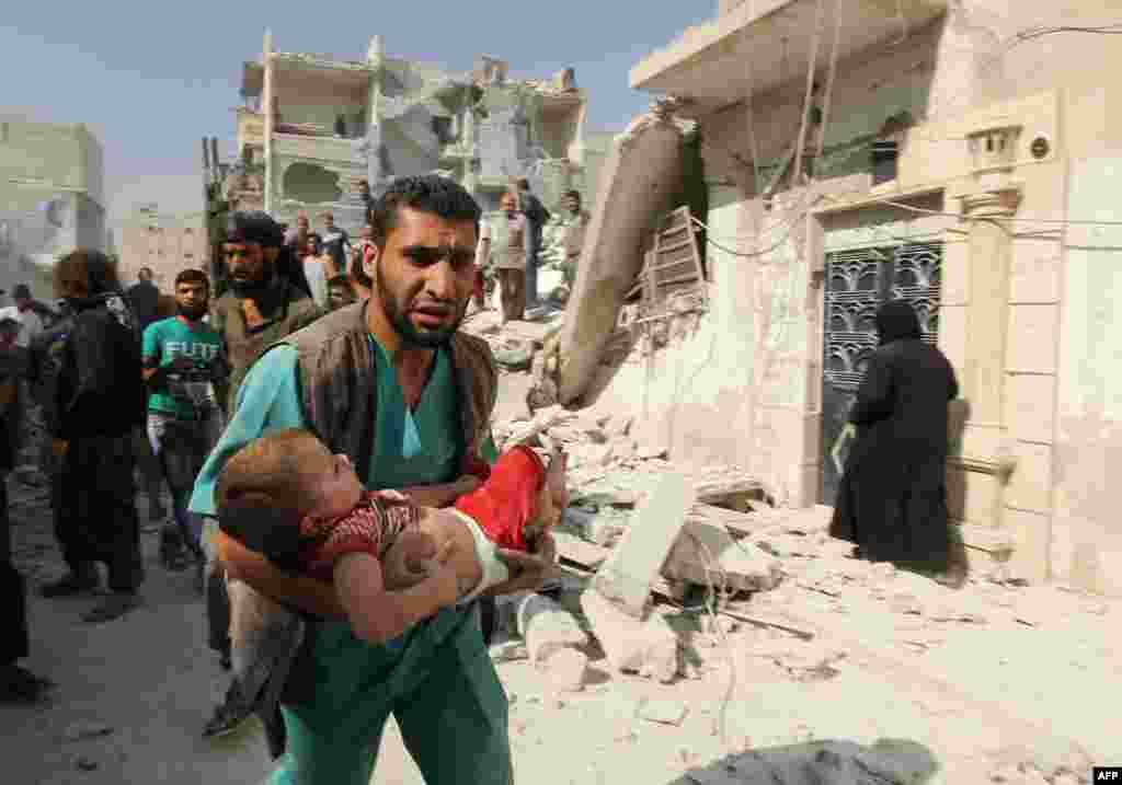 A man carries a wounded child following a government air strike on the rebel held Al-Maghair district of the northern Syrian city of Aleppo. Western Aleppo is controlled by regime forces while rebels are in the east of the city.