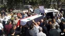 In this photo released by the Syrian official news agency SANA, mourners carry a coffin of one of the more than 200 people who were killed a day earlier by suicide bombings launched by the Islamic State's fighters on the eastern and northern countryside of the southern province of Sweida, in Sweida, Syria, July 26, 2018.