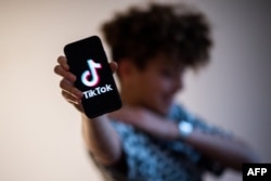 一名青少年拿着写有TikTok 图标的智能手机