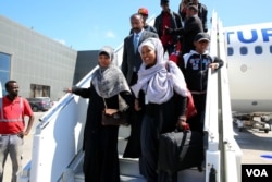 Somali migrants disembark from a plane upon arrival from Libya to be repatriated in their country at Mogadishu International Airport, Feb. 17, 2018. (H.K. Qoyste/VOA)