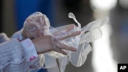 A visitor wears plastic gloves to help curb the spread of the coronavirus upon arrival at an exhibition hall in Goyang, South Korea, Dec. 4, 2021.