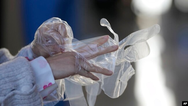 A visitor wears plastic gloves to help curb the spread of the coronavirus upon arrival at an exhibition hall in Goyang, South Korea, Dec. 4, 2021.