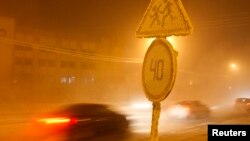 FILE - Cars pass by traffic signs covered with hoarfrost, with the air temperature at about minus 46 degrees Celsius (minus 50.8 degrees Fahrenheit), in the eastern Siberian city of Yakutsk in the Sakha (Yakutia) Republic, Jan. 16, 2013. 