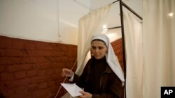 A nun exits a voting booth at a polling station in Budapest during the parliamentary elections in Hungary, Sunday, April 6, 2014. 