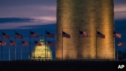 Flags around the Washington Monument fly in the breeze at daybreak. Tourism experts fear President Trump's travel ban may hurt tourism across the United States.