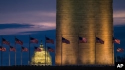 Flags around the Washington Monument fly in the breeze at daybreak, Dec. 31, 2015. Tourism experts fear President Trump's travel ban may hurt tourism across the United States.