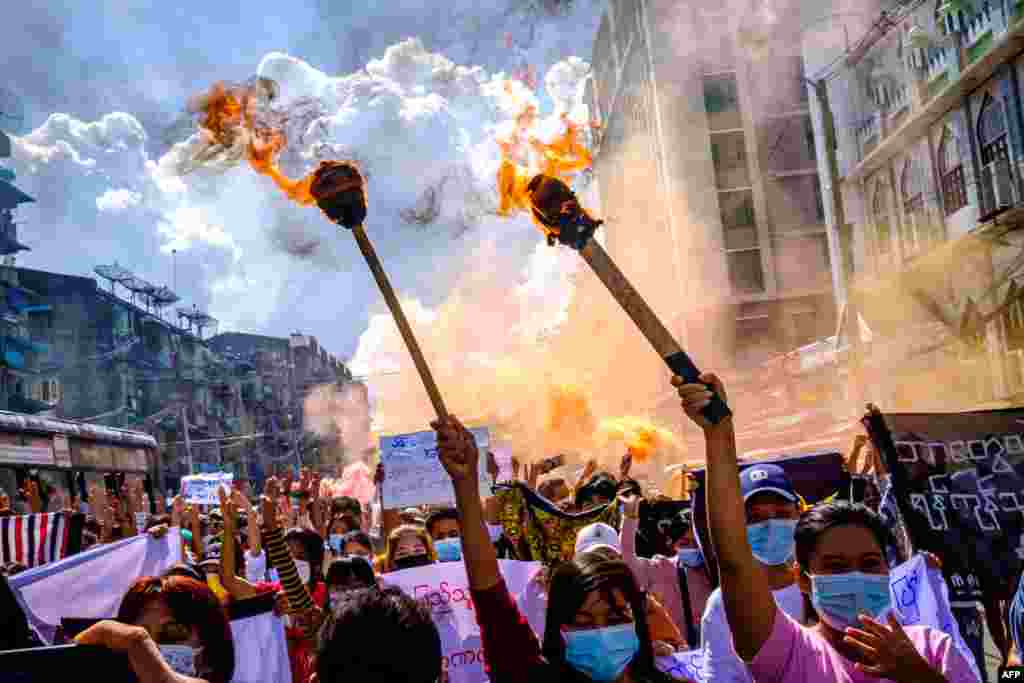 Women carry burning torches as they march during a demonstration against the military coup in Yangon, Myanmar.
