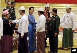 FILE - Aung San Suu Kyi, center, shakes hands with Senior General Min Aung Hlaing after the presidential handover ceremony in Naypyitaw, Myanmar, Wednesday, March 30, 2016.