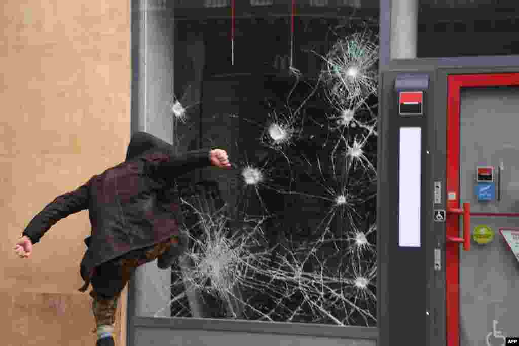 A protester smashes the window of a bank a during a 'Day of strikes' called by France's General Confederation of Labor (CGT) French worker's union in the French capital Paris.