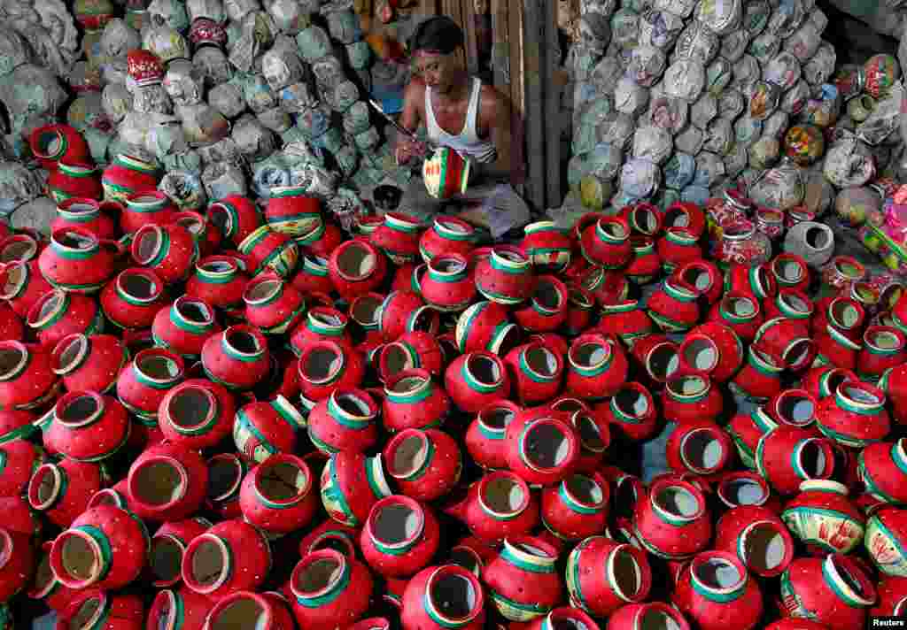 A man polishes an earthen pitcher typically used during Garba, a folk dance, inside a workshop ahead of Navratri, a festival during which devotees worship the Hindu goddess Durga and youths dance in traditional costumes, in Ahmedabad, India.
