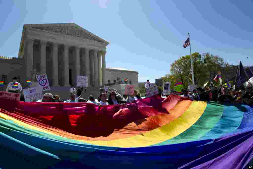 Demonstrators stand behind a rainbow flag in front of the Supreme Court in Washington, Tuesday, April 28, 2015.