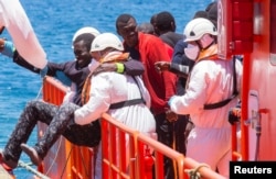 A migrant, who is part of a group of 58 intercepted aboard a makeshift boat around 100 miles off the coast, is helped by rescue workers upon arriving at Arguineguin port in the Canary Island Gran Canaria, Spain, May 30, 2016.