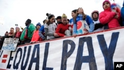 FILE - Fans stand behind a large sign for equal pay for the women's soccer team during an international friendly soccer match between the United States and Colombia in East Hartford, Conn., April 6, 2016. 