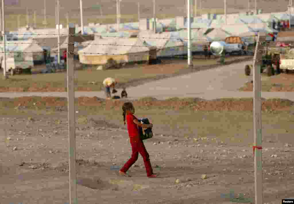 A displaced child from the minority Yazidi sect who fled violence in the Iraqi town of Sinjar, carries a jerry can filled with water at Bajed Kadal refugee camp, southwest of Dohuk, Sept. 15, 2014.