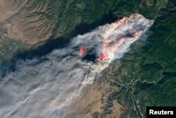 FILE - NASA's Operational Land Imager satellite image shows the Camp Fire burning at around 10:45 a.m. local time near Paradise, California, Nov. 8, 2018.