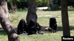 FILE - Veiled women sit in a garden in the northern province of Raqqa, Syria, March 31, 2014. The Islamic State has imposed strict new dress codes on women.