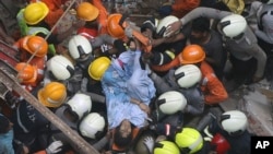 Rescuers carry out a survivor from the site of a building that collapsed in Mumbai, India, Tuesday, July 16, 2019. 
