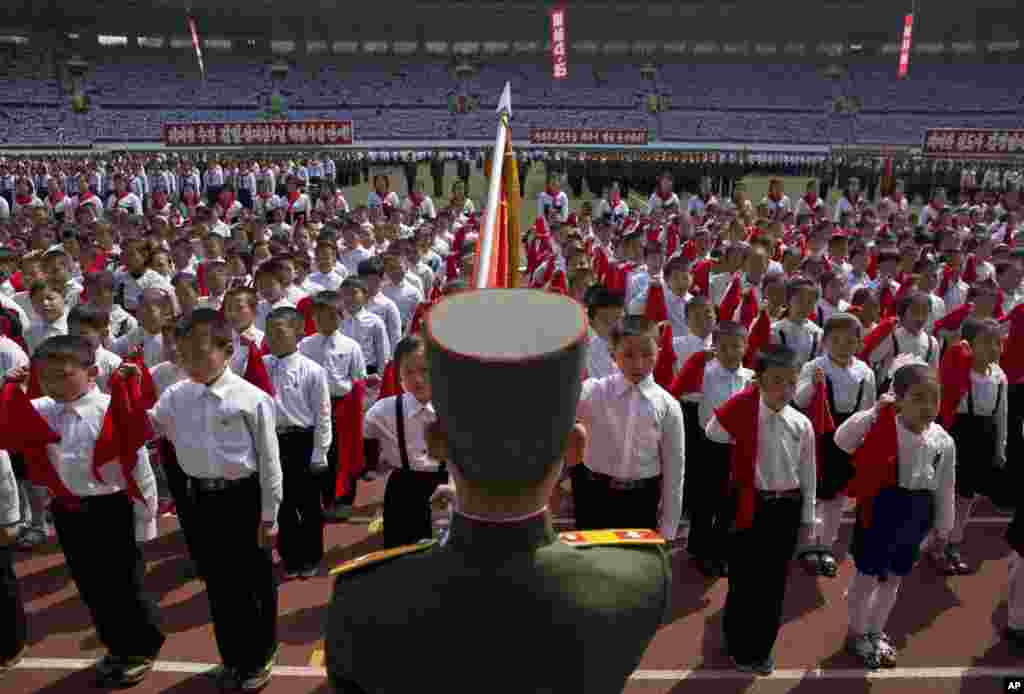 North Korean children hold up red scarves to be tied around their necks during an induction ceremony into the Korean Children&#39;s Union held at a stadium in Pyongyang, April 12, 2013.