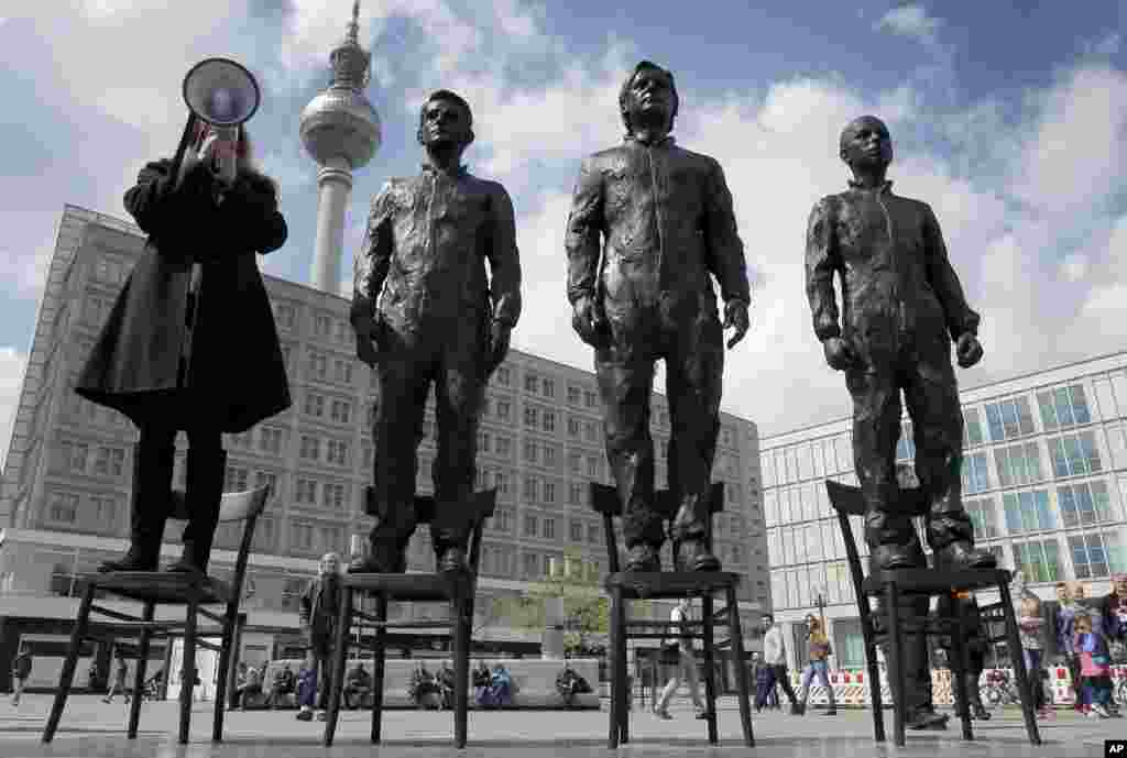 A women delivers a speech as she stands on a chair of the public art project "Anything to Say?" at the Alexander Square in Berlin, Germany, May 1, 2015.