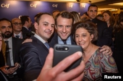 Emmanuel Macron, center, candidate for the 2017 French presidential election poses for a selfie with guests during the annual dinner of the Representative Council of France's Jewish Associations in Paris, Feb. 22, 2017.