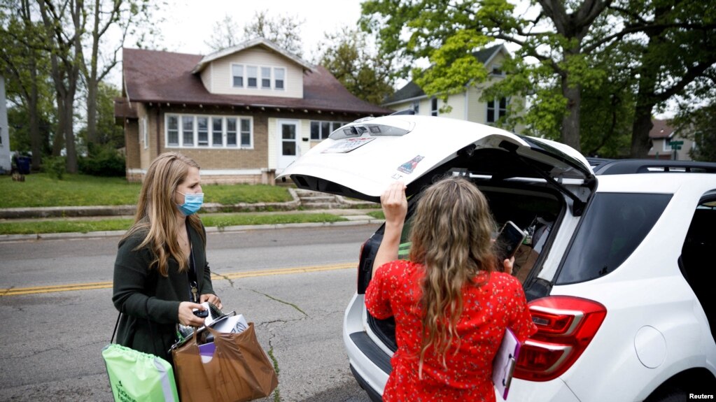 Rocking Horse Community Outreach Worker Amanda Ambrosio (left) and Hadley Smiddy (right) deliver food to a patient in the Purple Apron Program, which provides food, nutrition classes, and a supportive community for patients, in Springfield, Ohio, U.S., May 17, 2021. (REUTERS)