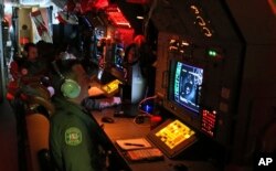 Aircrew man radars and sonar on board a Royal Australian Air Force AP-3C Orion as they search for the missing Malaysia Airlines Flight MH370 in southern Indian Ocean, Australia, Mar. 22, 2014.