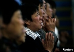 FILE - A woman prays with other villagers during a mass in the morning at the Liuhe Catholic Church in Liuhe village on the outskirts of Qingxu county, northern China's Shanxi province, Sept. 11, 2011.