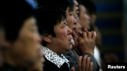 FILE - A woman prays with other villagers during a mass in the morning at the Liuhe Catholic Church in Liuhe village on the outskirts of Qingxu county, northern China's Shanxi province, Sept. 11, 2011.