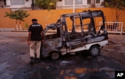 A policeman inspects a vehicle burned by Mutahida Qaumi Movement (MQM) political party protesters, in Karachi, Pakistan, Aug. 22, 2016.