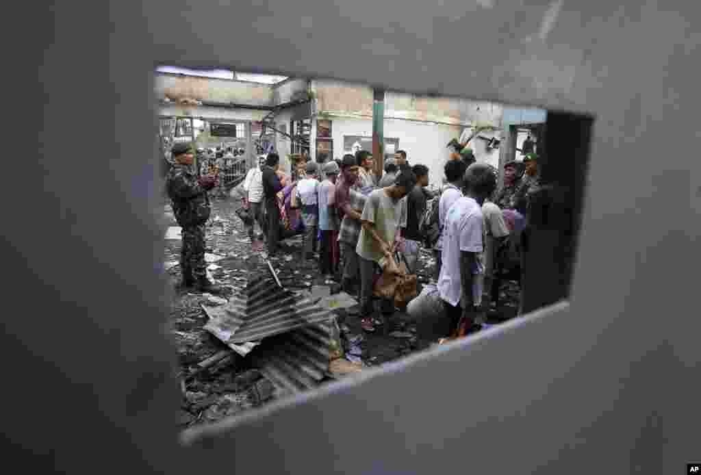 Indonesian soldiers stand guard as inmates line up before being transferred to other prisons, at Labuhan Ruku prison that was burnt after a riot, Batubara, North Sumatra. 