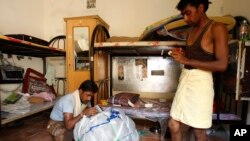 FILE - Indian laborer, Kumar, left, helps his room- mate, Shree Bhagwan, to pack his bag at the Al Sajaa camp in Sharjah, United Arab Emirates.