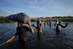 包括很多海地人在内的移民离开德克萨斯州的德尔里奥，淌水越过格兰德河，返回墨西哥一侧，有些人是为了躲避美国遣返，有些人则是为了补充物资。(2021年9月22日)