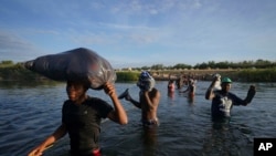 Migrants, many from Haiti, wade across the Rio Grande river to leave Del Rio, Texas, and return to Ciudad Acuna, Mexico, Sept. 22, 2021, some to avoid possible deportation from the U.S. and others to load up with supplies.