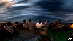 FILE - Migrants and refugees stand on the deck of the rescue vessel Golfo Azzurro after being rescued by Spanish NGO Proactiva Open Arms workers on the Mediterranean Sea, June 16, 2017. 