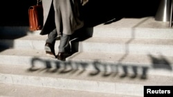 FILE - A man walks past the shadow of the logo of Swiss bank Credit Suisse in Zurich.