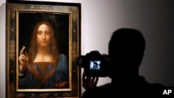 FILE - A visitor films Leonardo da Vinci's "Salvator Mundi" on display at Christie's auction rooms, in London, Oct. 24, 2017. 