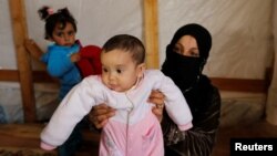 Syrian refugee Asheqa holds her unregistered baby daughter Nour inside a tent at a refugee camp near the town of Baalbek in Lebanon's Bekaa valley, March 3, 2016. 