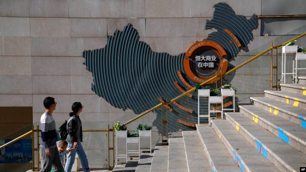 2021 年 9 月 21 日，在北京恒大城市广场，一家人走过一张显示中国恒大发展项目的地图。(photo:VOA)