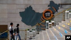 A family walks by a map showing Evergrande development projects in China at an Evergrande city plaza in Beijing, Sept. 21, 2021.