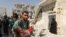 A man carries a wounded child following a government air strike on the rebel held Al-Maghair district of the northern Syrian city of Aleppo. Western Aleppo is controlled by regime forces while rebels are in the east of the city.