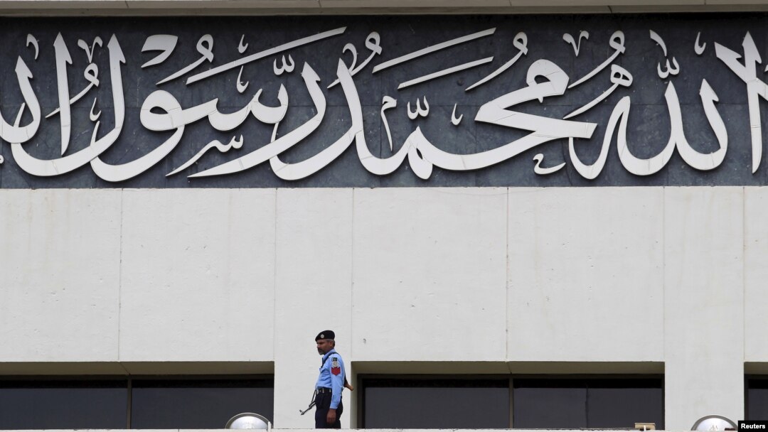 FILE - A police officer keeps guard near an religious inscription on the Parliament building in Islamabad, April 7, 2015. 