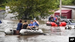 Petugas layanan darurat memberikan bantuan di desa yang dilanda banjir di wilayah Primorye, Rusia Timur Jauh setelah hujan deras akibat Topan Khanun melanda wilayah tersebut, Minggu (13/8). 