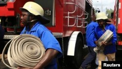 Firefighters carrying fire hoses run at the scene of a fire which broke out at the headquarters of the Nigeria Football Federation in Abuja, August 20, 2014.