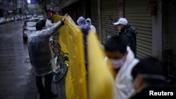 湖北省武漢市是中國冠狀病毒病爆發的重災區，戴著口罩的工人正在修復街道上的障礙物。（2020年3月29日）