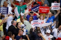 FILE - Supporters wave signs as President Donald Trump speaks at a campaign rally at U.S. Bank Arena, in Cincinnati, Ohio, Aug. 1, 2019.