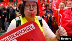 A supporter of the Confederation of German Trade Unions (DGB) blows a whistle as she takes part in a union rally for "political change" in Frankfurt, Sept. 7, 2013. 