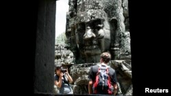 A tourist poses for photographs in the Bayon Temple in the northern province of Siem Reap, about 320 km (199 miles) from Phnom Penh August 31, 2010. Tourist arrivals to Cambodia increased by 14 percent to 1.42 million people, during the first seven months this year as compared to the same period in 2009, said Kong Sophearak, Director of Statistics at the Tourism Ministry. REUTERS/Chor Sokunthea 