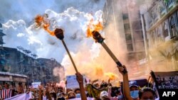 Women carry burning torches as they march during a demonstration against the military coup in Yangon, Myanmar.