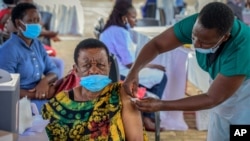 FILE - A woman receives a coronavirus vaccination at the Kololo airstrip in Kampala, Uganda, May 31, 2021.